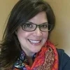 Head and shoulders bio photo of Shelley Ewing wearing glasses and red scarf with dark color shirt